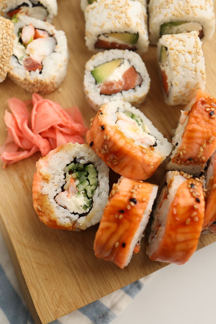 A delicious assortment of sushi rolls served on a wooden board with pickled ginger.