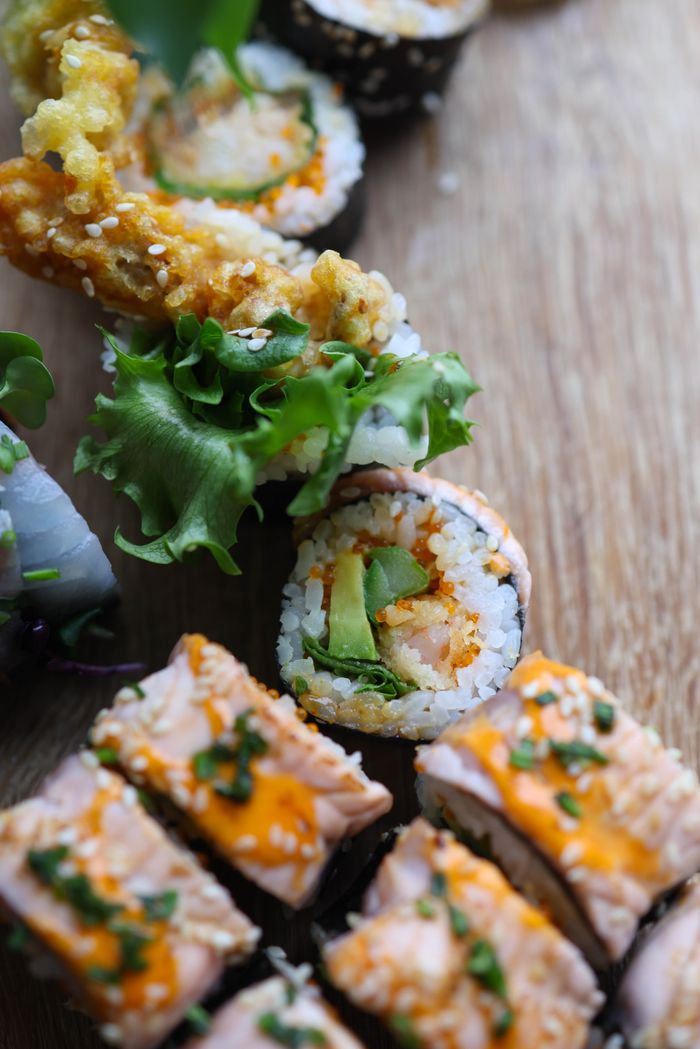 Delicious close-up of sushi rolls with fresh vegetables and seafood on a wooden board.